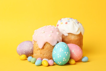 Fototapeta na wymiar Easter eggs and cakes on yellow background, space for text