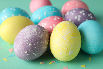 Multicolor Easter eggs on mint background, close up