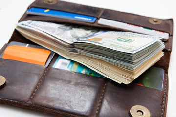 Stack of dollars and credit cards in a leather wallet