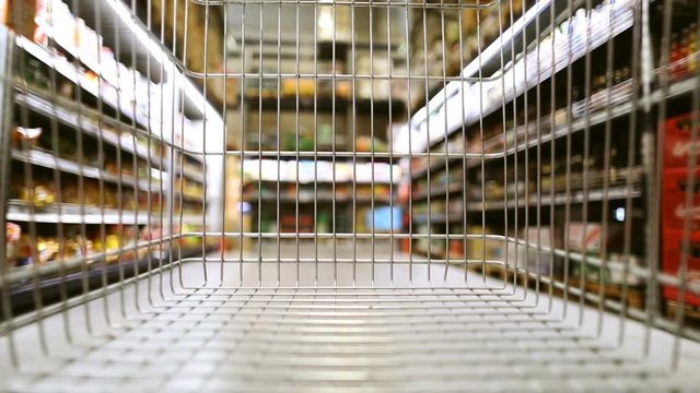 Empty shopping cart moving through supermarket in slow motion