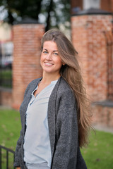 Romantic and cheerful young woman. Portrait of a Beautiful girl in jeans, a blue shirt, and a light coat. Walks the streets of the city.