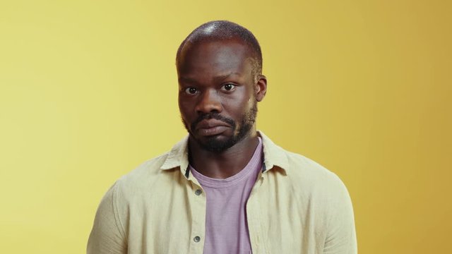 Doubtful african young man expresses his innocence shrugging shoulders at camera posing in the studio. Doubts, hesitation. Emotions concept.