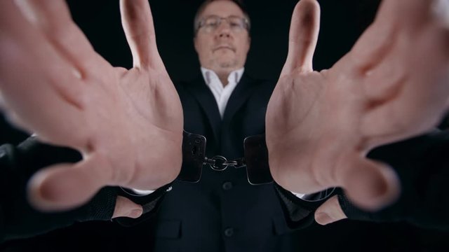 Police Officer Handcuffs Hands Of Arrested Middle Aged Man In Suit. Arrest Of Corrupt Official For Committing Illegal Money Laundering Actions. Anti-corruption Concept In Government And Business