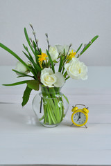 Glass vaza with a bouquet of spring flowers and yellow alarm clock .Bunch of pussy willow branches with catkins and white roses.Spring card for Mother's Day, Women's Day. copy space.