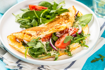 Omelette with green leaves at white plate.