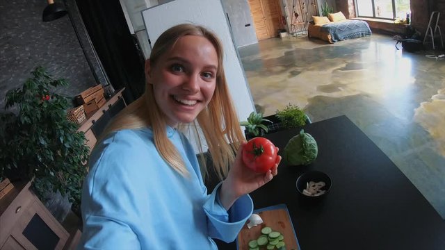 Young beautiful blonde takes on videos as she cooks in the kitchen
