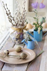 Easter decoration, eggs, pussy-willow branches on a wooden surface on a window background