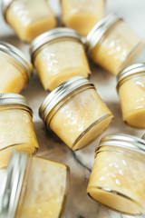 Homemade honey butter in glass jars on marble background