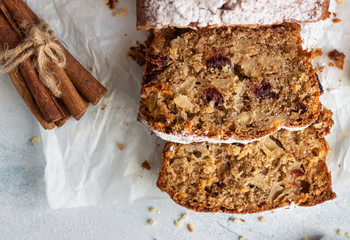 Spicy apple, nuts and dried cranberry loaf cake decorated with powdered sugar on a paper.