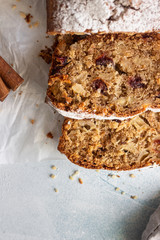 Spicy apple, nuts and dried cranberry loaf cake decorated with powdered sugar on a paper.