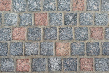 texture. stone paving of square granite stones of gray and reddish colors