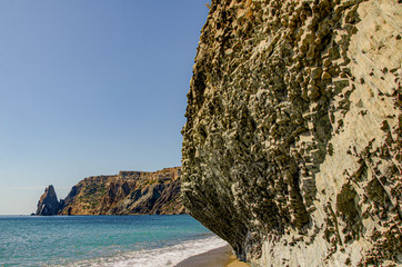 Mountain landscape, large cliffs by the sea, beach, sunny day.