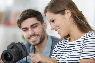 young couple looking photos on the camera at home