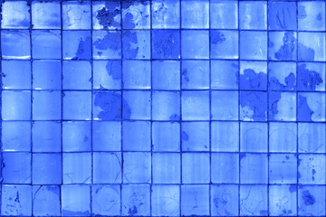 Blue tile background. Old rough paint on the wall. Square blocks.