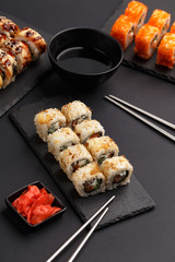 Sushi rolls on colored plates on a black background. A look from above.