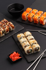 Sushi rolls on colored plates on a black background. A look from above.