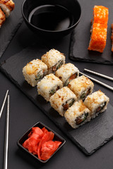 Sushi rolls on colored plates on a black background. A look from above.