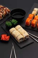 Sushi rolls on colored plates on a black background. A look from above.