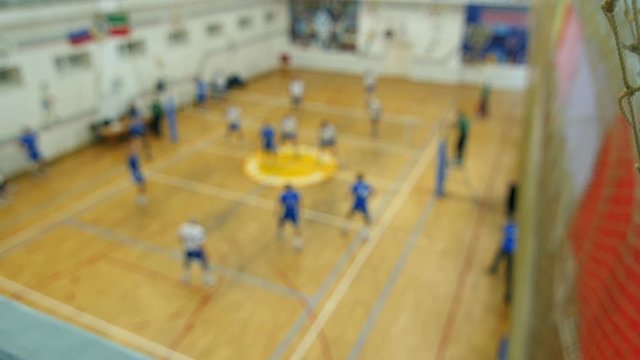 "Dolly camera from the volleyball nets on the General view of the hall. On the background in the gym men playing volleyball. Flow and goal with live sound.  Background"
