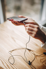 Obraz na płótnie Canvas girl puts black wired headphones into the phone