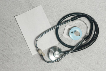 Stethoscope, phonendoscope and baby nipple on the marble.