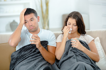 young couple blowing their nose in tissue at home
