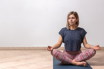Beautiful young woman working out in loft interior on white background with copy space, doing yoga...