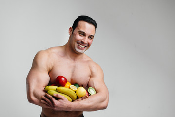 Sporty sexy guy posing on a white background with bright fruits. Diet. Healthy diet