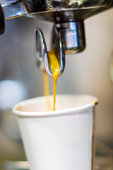 close up of Coffeemaker pouring coffee into a paper cup.