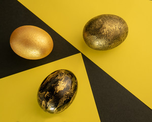 Bright Easter. Eggs are black and gold on the background of a geometric pattern.