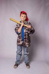 Child boy in jeans and a protective jacket in a red cap with a bat on a white background