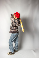 Child boy in jeans and a protective jacket in a red cap with a bat on a white background