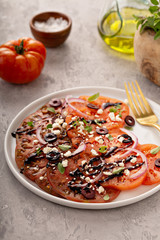 Fresh heirloom tomato carpaccio salad with red onions, olives, herbs and balsamic glaze