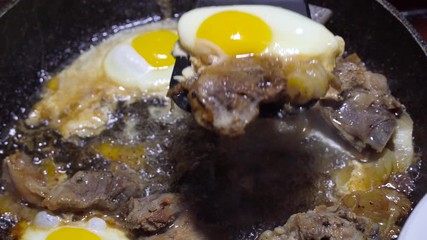 eggs and pork are fried in a pan in fat. The concept of poor and not healthy eating. Put a spatula on a plate.