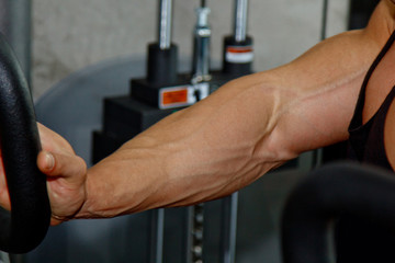 Male powerful biceps closeup. Gym. Body-builder. Beautiful, swollen male body. Trainer, advertising, healthy lifestyle. Bodybuilder. The concept of sports.