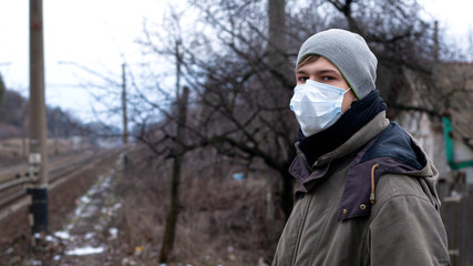 Fototapeta na wymiar young man in medical disposable mask standing near the station. viral disease protection flu, SARS, Covid-19