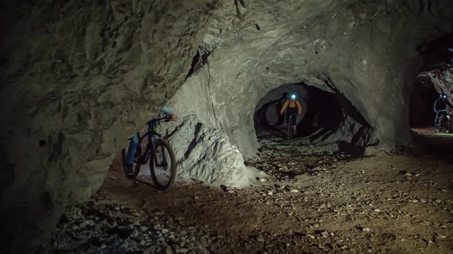 Underground cave mountain biking. Dark mysterious cave path. Slowmotion. Mežica, Slovenia