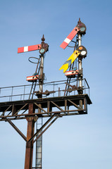 Simple view of traditional mechanical railway semaphore signal with pivoted arms on a rusted post at a British train junction