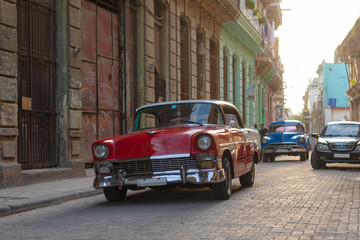 Naklejka premium vintage red classic car on cobblestone street in front of old house in havana, cuba