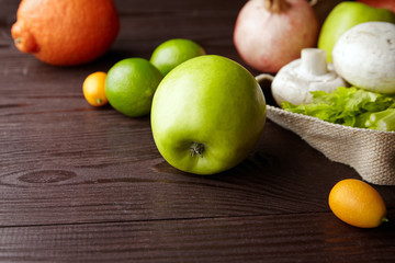 Shopping bag with fresh fruits and vegetables on wooden table