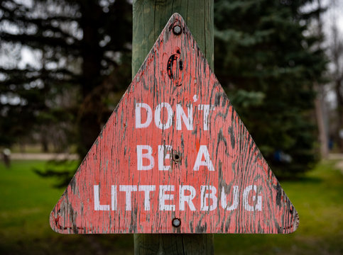 Old dilapidated &ldquo;Don&rsquo;t be a Litterbug&rdquo; sign.  The pink paint is pealing.  Green trees can be seen in the background.