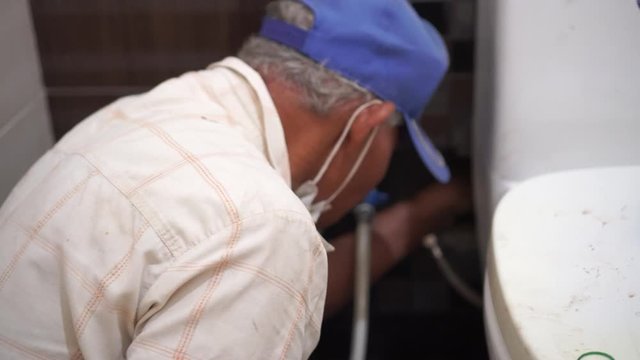 Technician Asian elderly plumber Repairing broken water pipes in bathroom, Worker  builder, repairman with Tools Repair Leaking Pipe. Talented foreman elderly people adjustable wrench holds plumbing