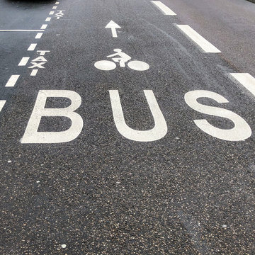 Photo d'une voie de circulation réservée aux bus et vélos en gris et blanc avec emplacement de stationnement pour taxi