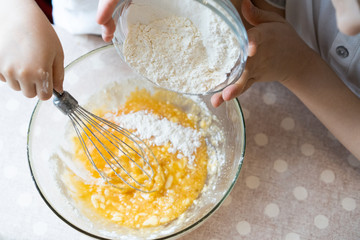 the process of making dough for pancakes with ingredients on a light table, eggs and flour are whipped with a mixer