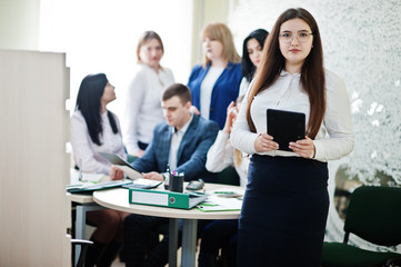 Portrait of caucasian woman in white blouse and eyeglasses hold tablet against business people...