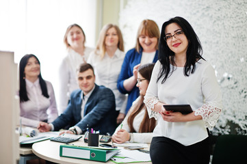 Portrait of caucasian woman in white blouse and eyeglasses  hold tablet against business people...