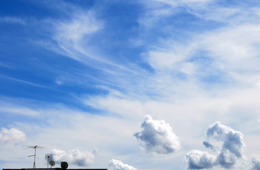 Small tv antennas and blue sky background with clouds
