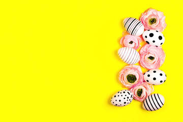 Fototapeta premium Creative graphic hand-painted eggs and ranunculus flowers on bright yellow background. Easter concept.