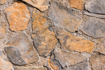 Texture of an old wall with fragments of natural stone and cement.
