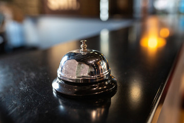 Stylish metal bell for calling a bartender or waiter on the bar counter. Bell restaurant on the bar with bokeh